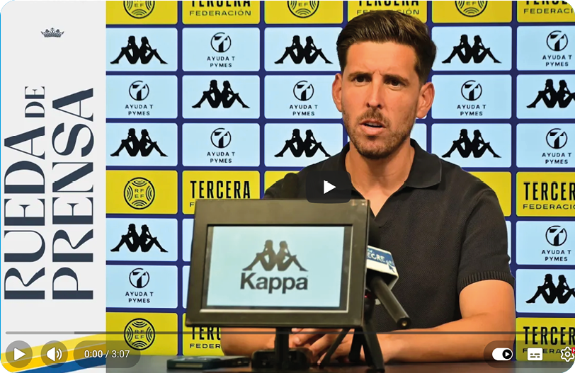 A person with short styled hair wearing a black polo shirt is speaking at a press conference with a backdrop featuring logos and a microphone in front of them. Descripci n generada con IA