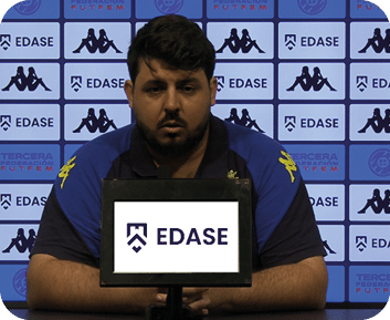 Una persona con camiseta deportiva azul y negra est sentada frente a un micr fono con un cartel que muestra el logo y nombre de EDASE, con un fondo repetitivo de logos y texto relacionados.  Descripci n generada con IA